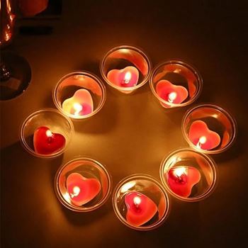Hořící svíčky ve tvaru srdce vyskládané do kruhu